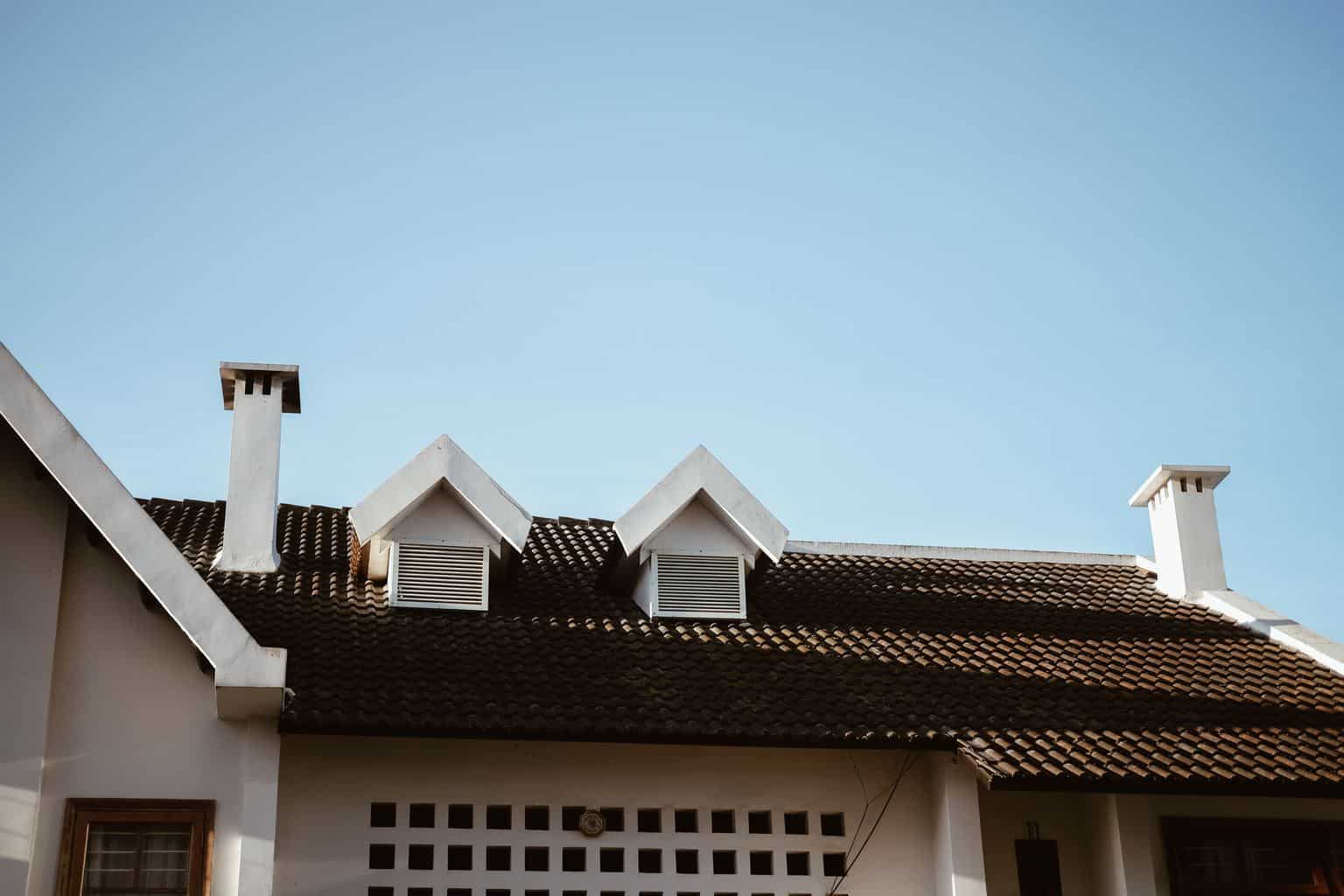 Image shows a black shingled roof, on a white home