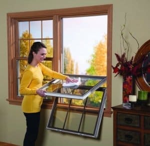 Image shows a woman cleaning a double hung window from the inside
