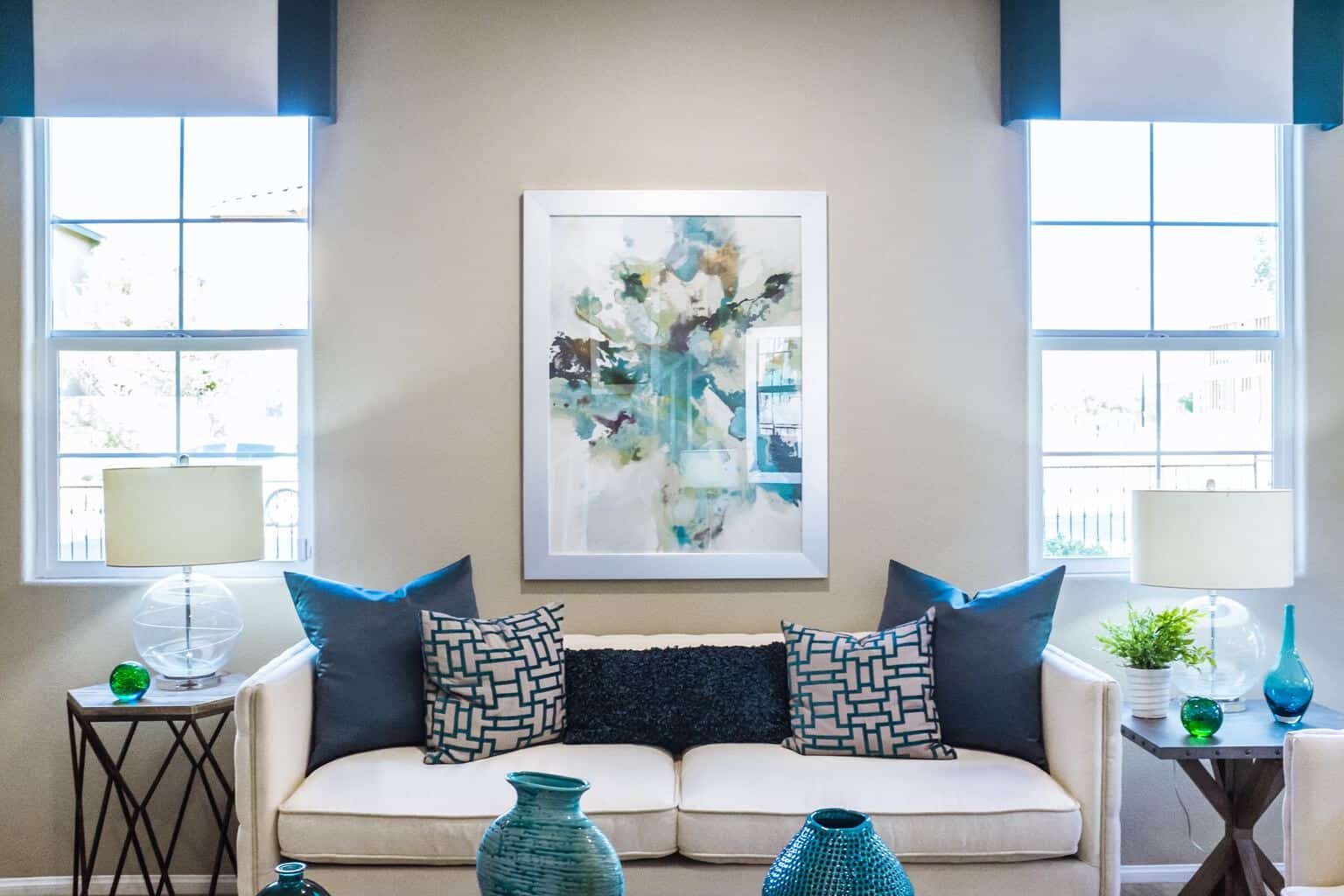 Image shows a white living room with blue accent pillows and curtains