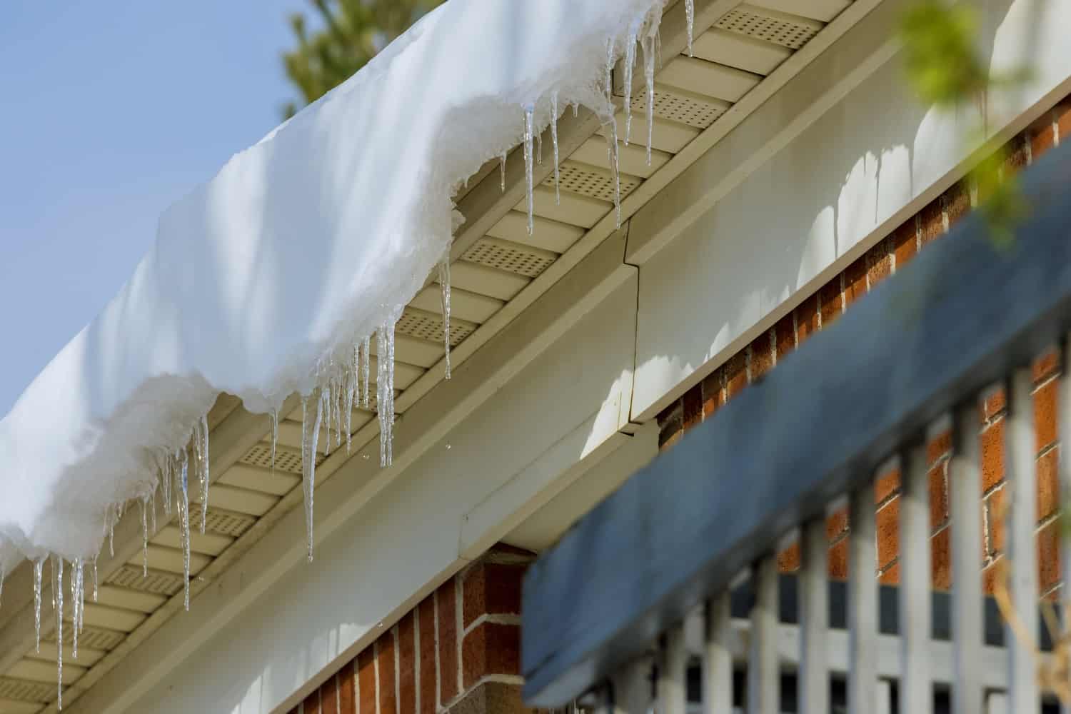 Snow and frozen icicles hang over the gutters of a home.